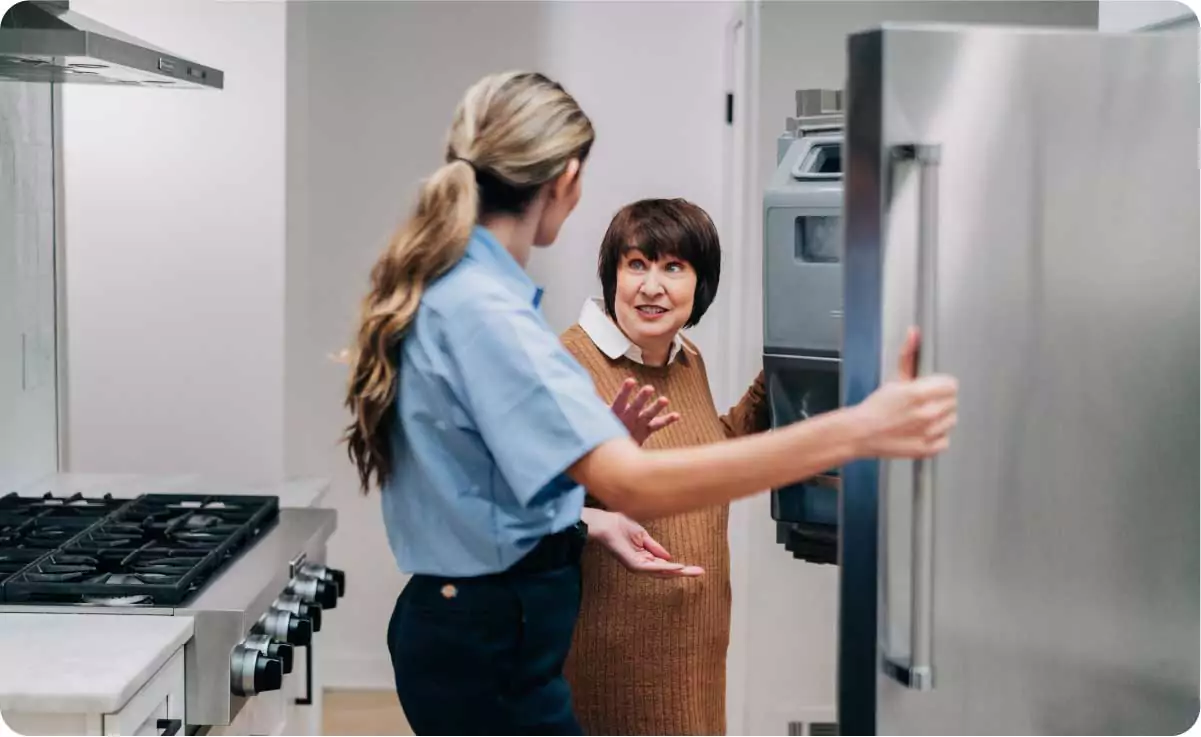 Photo of an appliance service professional speaking with a customer in front of an open fridge