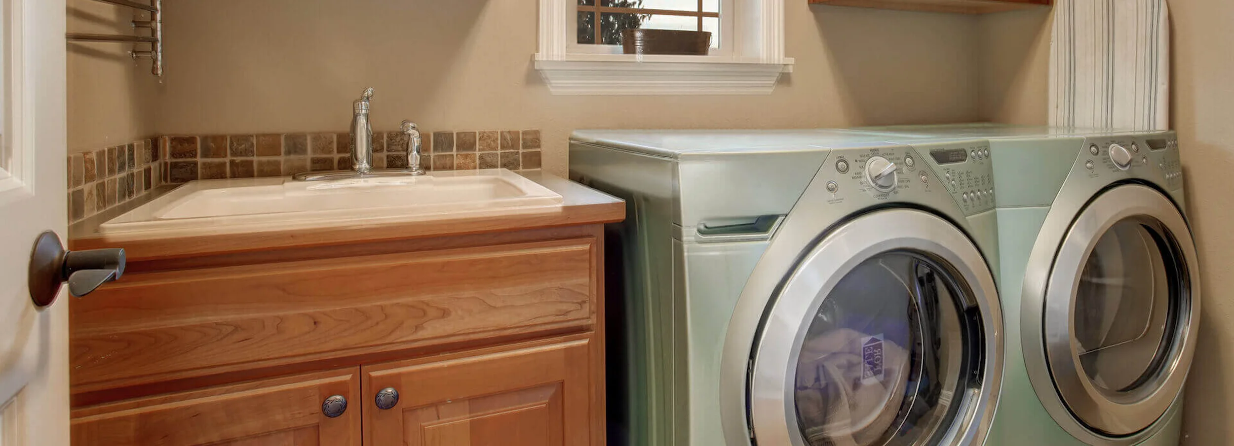 Gray washing machine and dryer beside sink in tidy home laundry room.