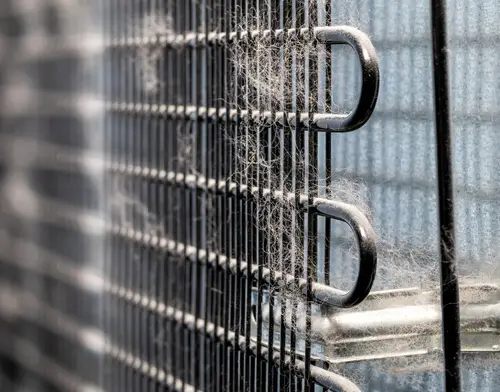 Dirty condenser coils at the back of a refrigerator.