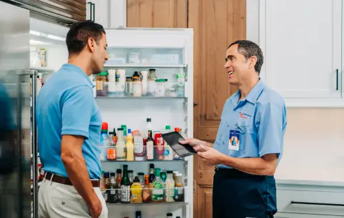 Mr. Appliance service professional assisting a homeowner with refrigerator trouble.