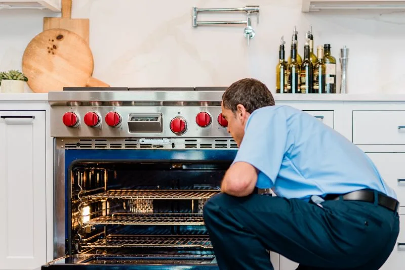 Mr. Appliance repairman inspecting an oven.
