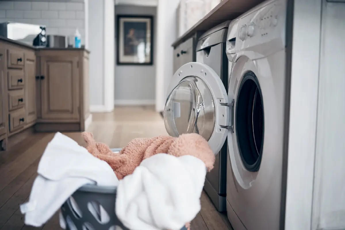 Laundry basket of towels being unloaded from a dryer.