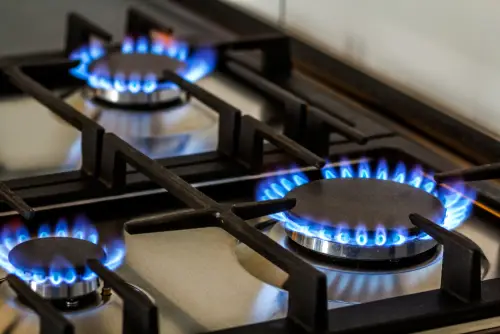 Gas stovetop with three lit burners.